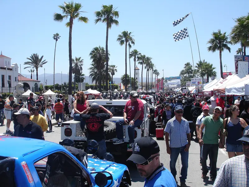 Race fans walk among off-road race vehicles at the 2008 Baja 500 contingency
