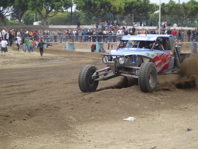 Buggy de carreras levanta tierra frente al público detrás de una barda en la Baja 500 de 2007