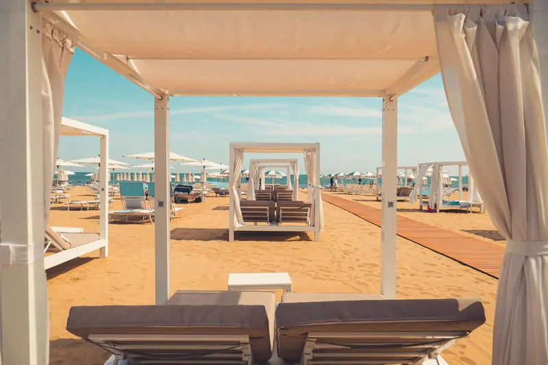Cabañas blancas con camastros sobre la arena, ejemplo de un club de playa