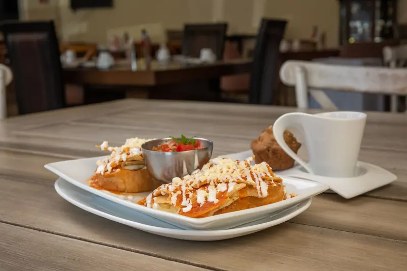 Plate of chilaquiles with salsa and a cup of coffee on a breakfast table