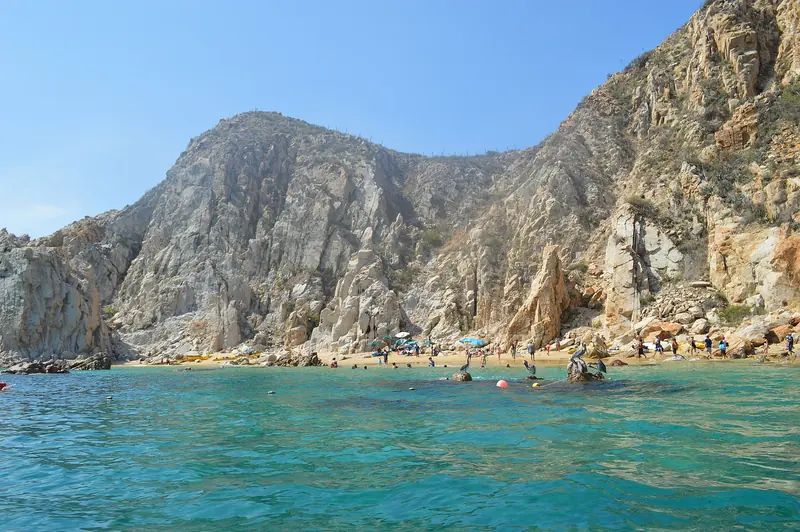 Snorkelers in the calm water at Lover's Beach below the granite cliffs of Land's End