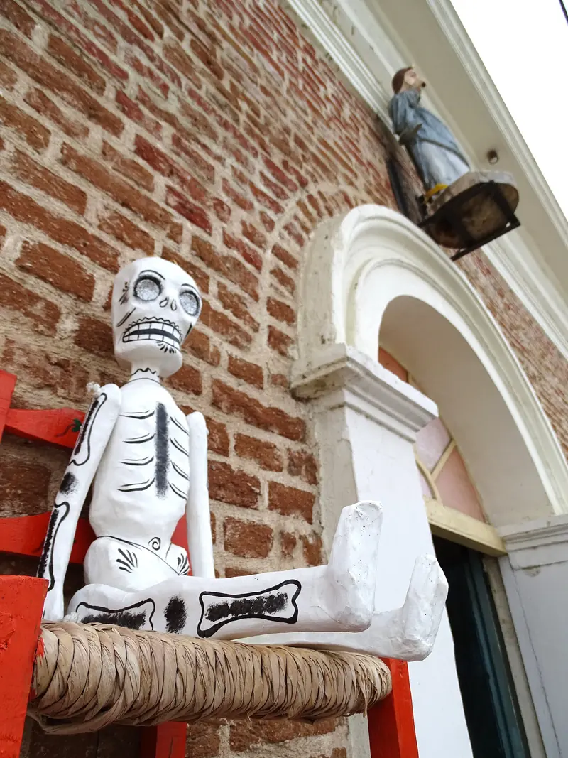 Brick facade in Todos Santos with a white papier-mâché skeleton seated in a chair