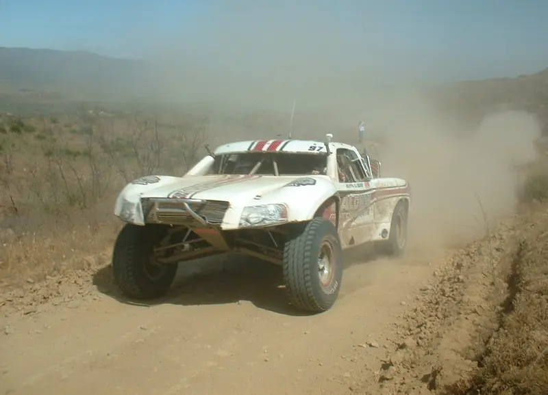 Off-road trophy truck kicking up dust on a desert dirt track