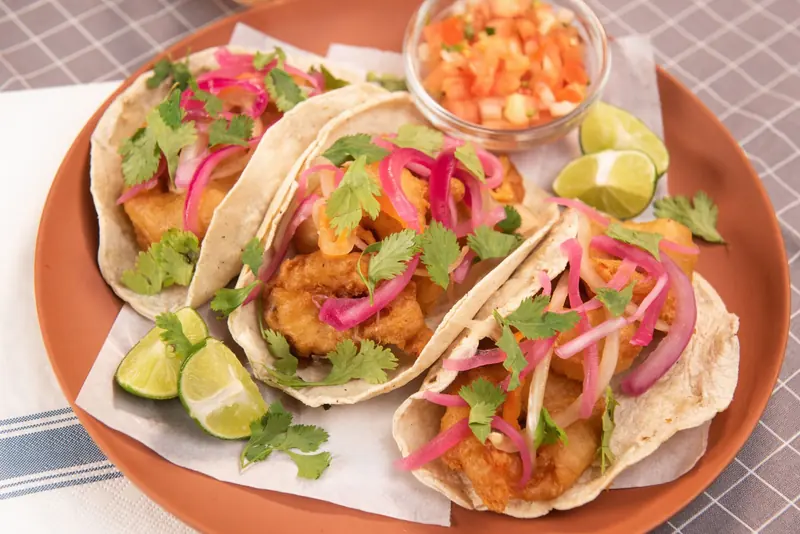Tacos de pescado con cebolla morada, cilantro y limón en un plato
