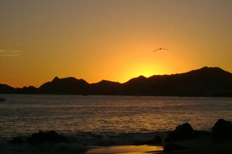 The sun setting behind the dark hills along the bay