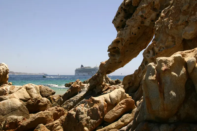 Rocks at Lover's Beach with a cruise ship anchored in the bay behind them