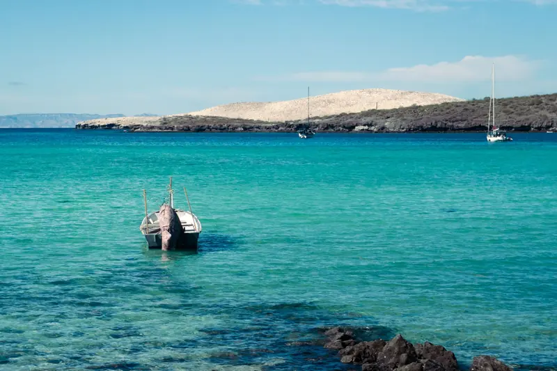 A small boat and a sailboat on turquoise water off the La Paz coast