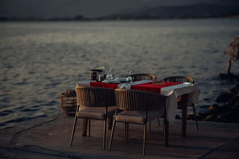Mesa para dos puesta en un muelle sobre agua tranquila al anochecer