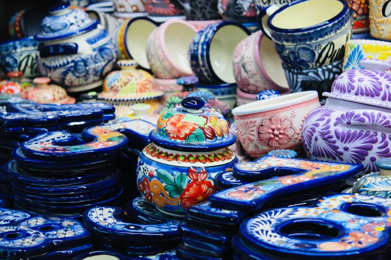 Stacks of Talavera pottery painted in blue and multicolored patterns at a market