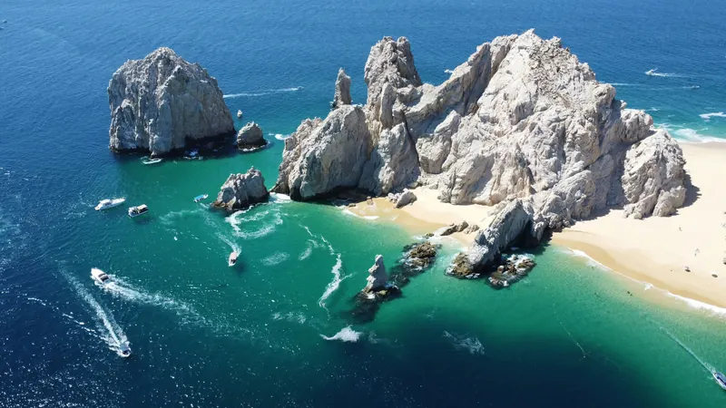 Lover's Beach and the rocks of Land's End from the air, with small boats in the clear water