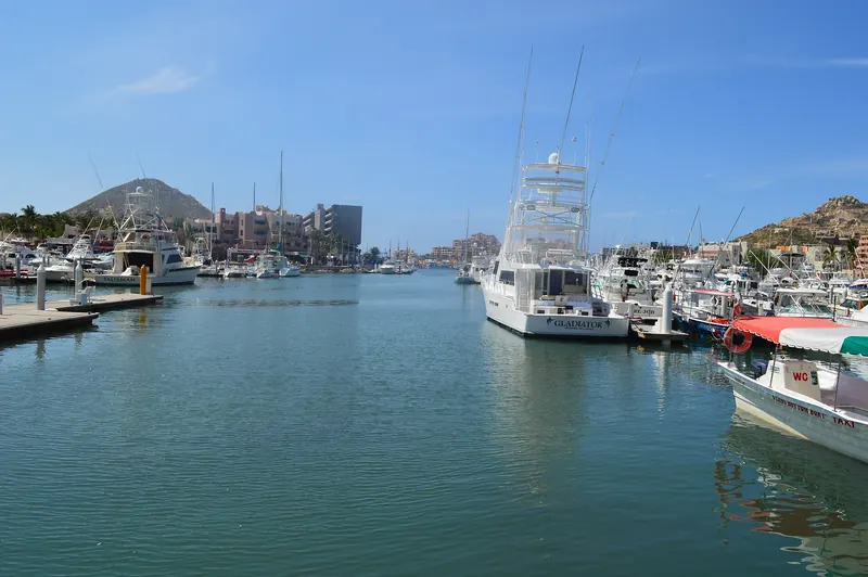 Calm water inside Marina Cabo San Lucas on a clear day, with yachts tied up along the docks