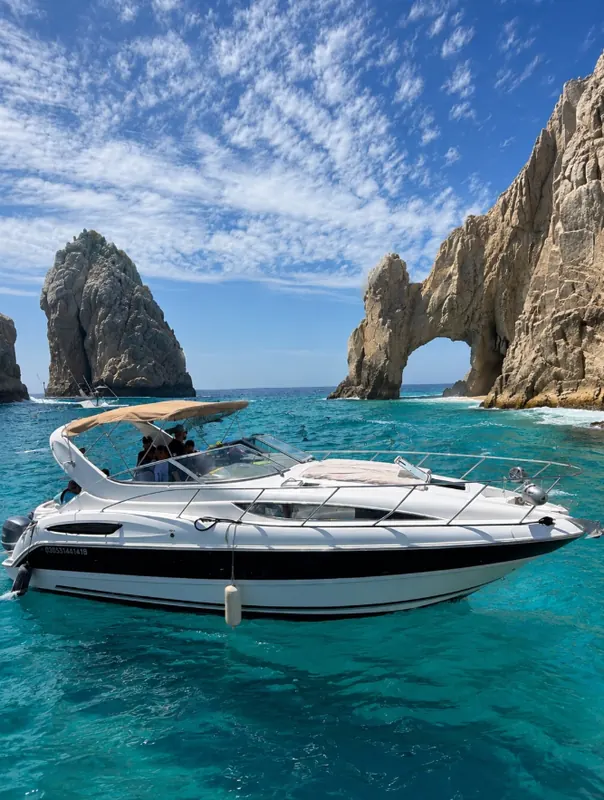 The Bayliner 33 express cruiser on turquoise water in front of the Arch at Land's End