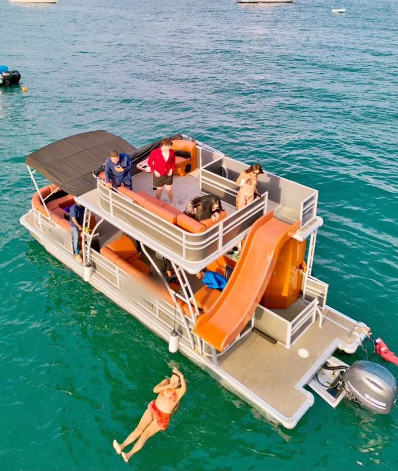 The Pontoon 38 seen from above at anchor with its slide down and a swimmer in the water beside it