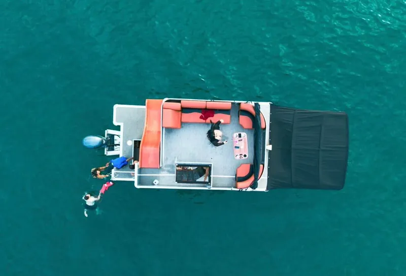 Aerial view of the Pontoon 38 party boat anchored in turquoise water with guests swimming off the stern