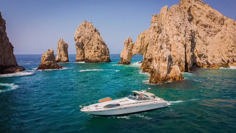 Sea Ray 65 express motor yacht cruising past the Arch at Land's End in Cabo San Lucas