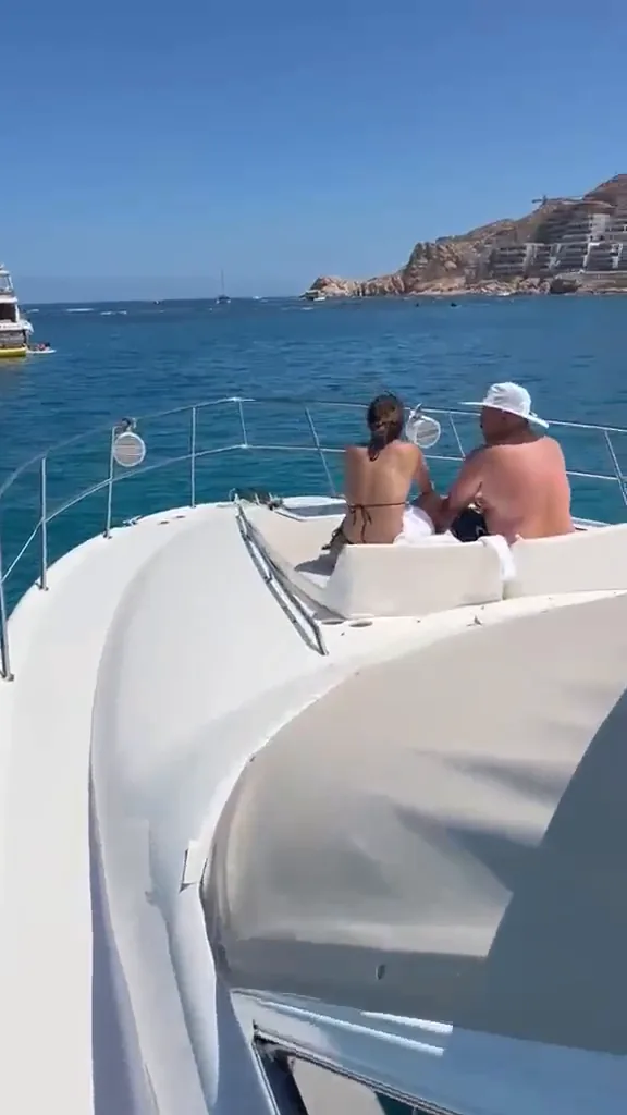 Walking the side deck of the Sea Ray 55 to the bow, where a couple sits on the sun pads facing the beach